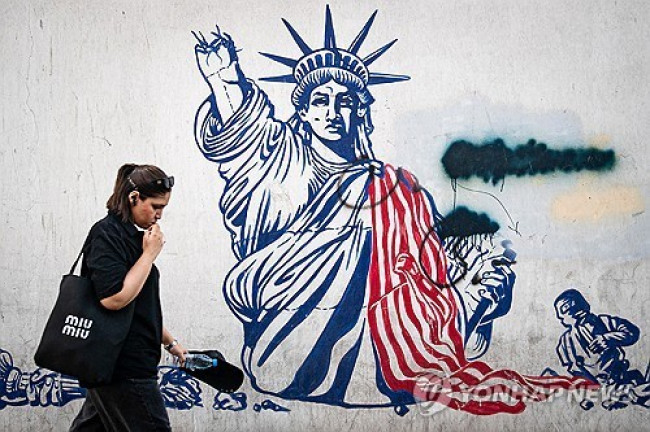 A woman walks past an anti-US mural in Tehran