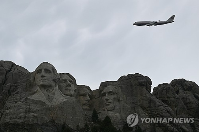 Air Force One flying over Mount Rushmore featuring the faces of former U.S. presidents